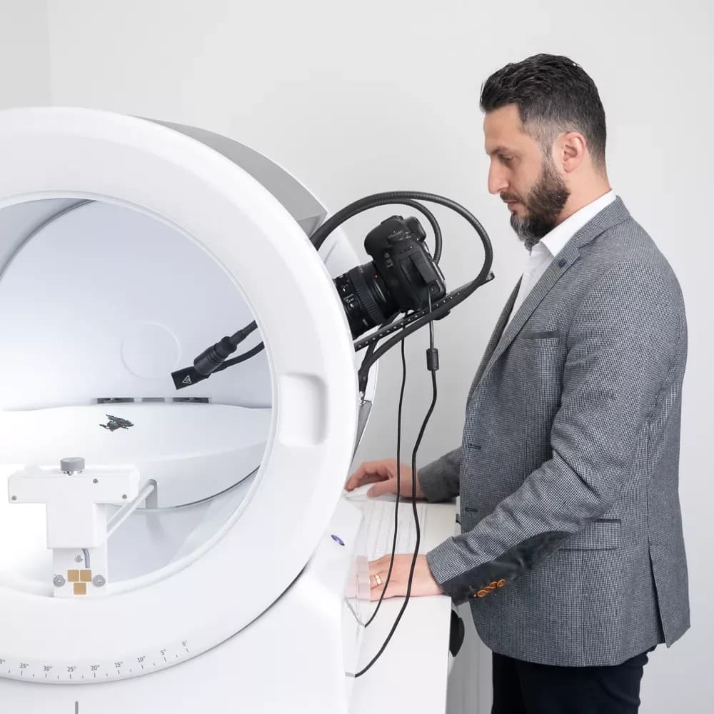 Hombre con traje operando un dispositivo de fotografía Orbitvu