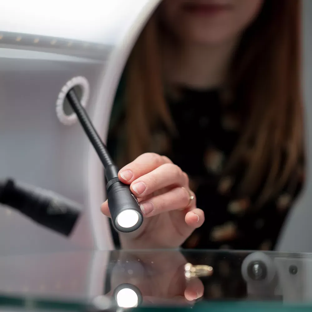 Mujer ajustando la luz LED en una configuración de fotografía de joyería