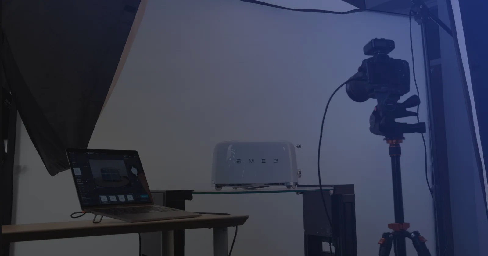 Set de fotografía de producto con tethering: una notebook con el software de captura junto a una cámara en trípode y un producto sobre un estante de vidrio