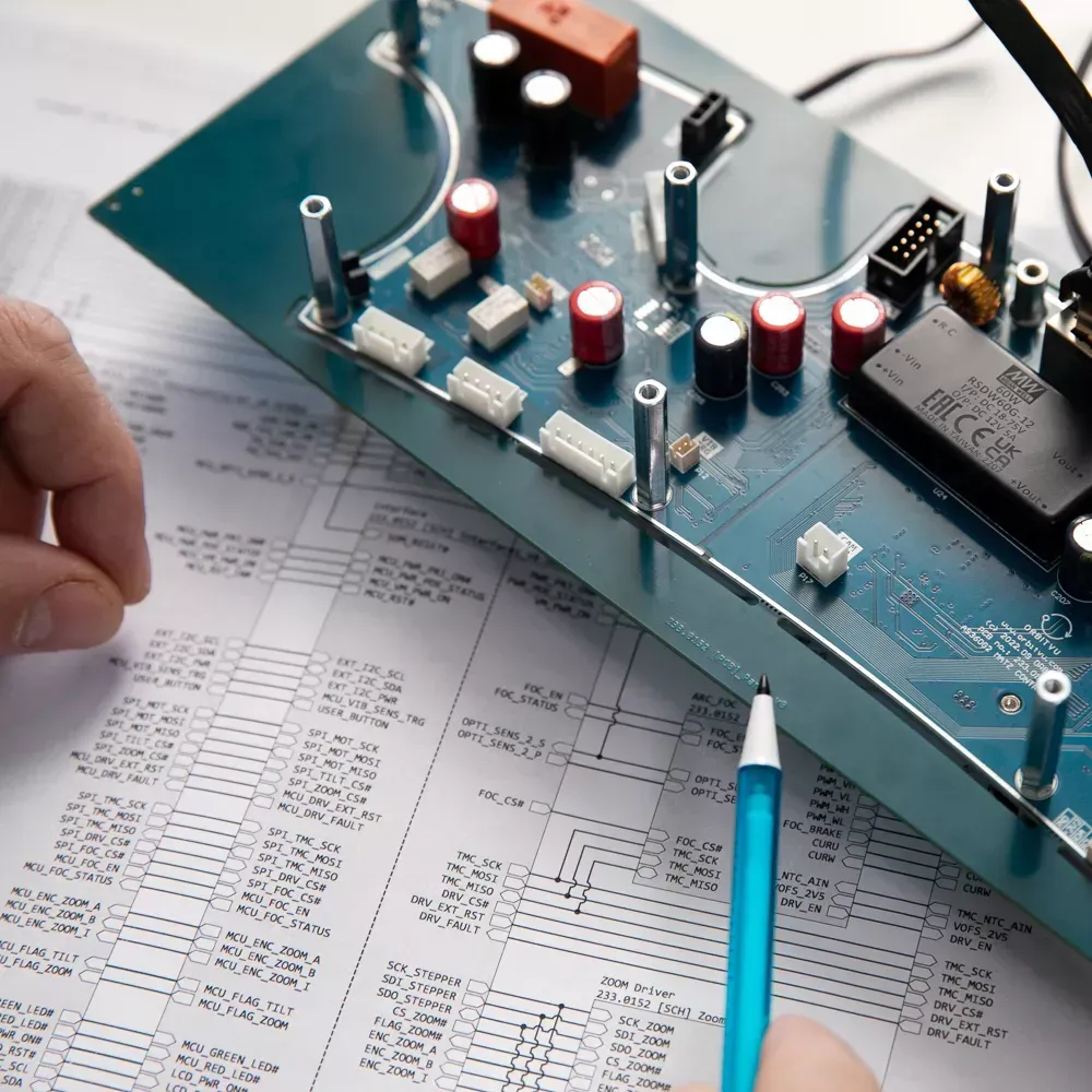 Ingeniero revisando una placa de circuito electrónico y un diagrama esquemático